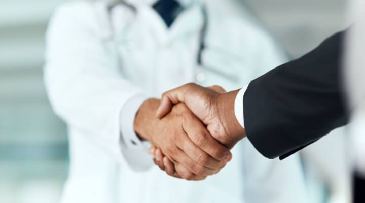 Physician shaking hand with business man